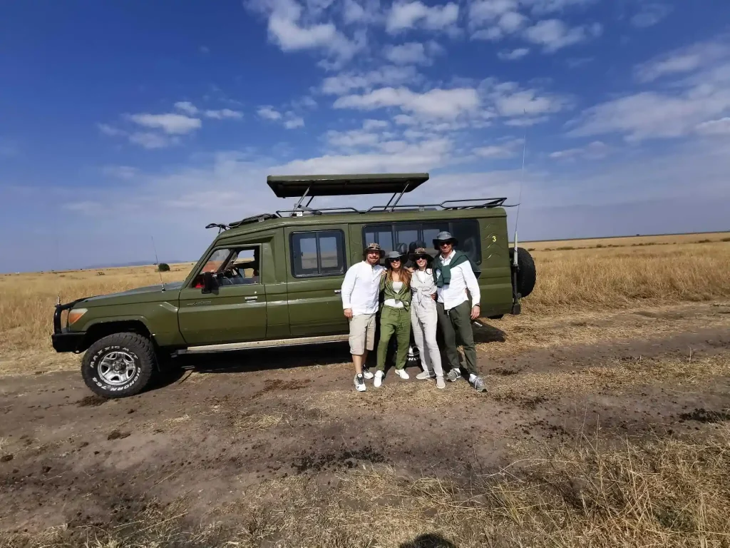 A family in front of their green 4x4 safari Land Cruiser on the open savanna plains during a 9-day Kenya family safari with Ahot Sun Safaris.