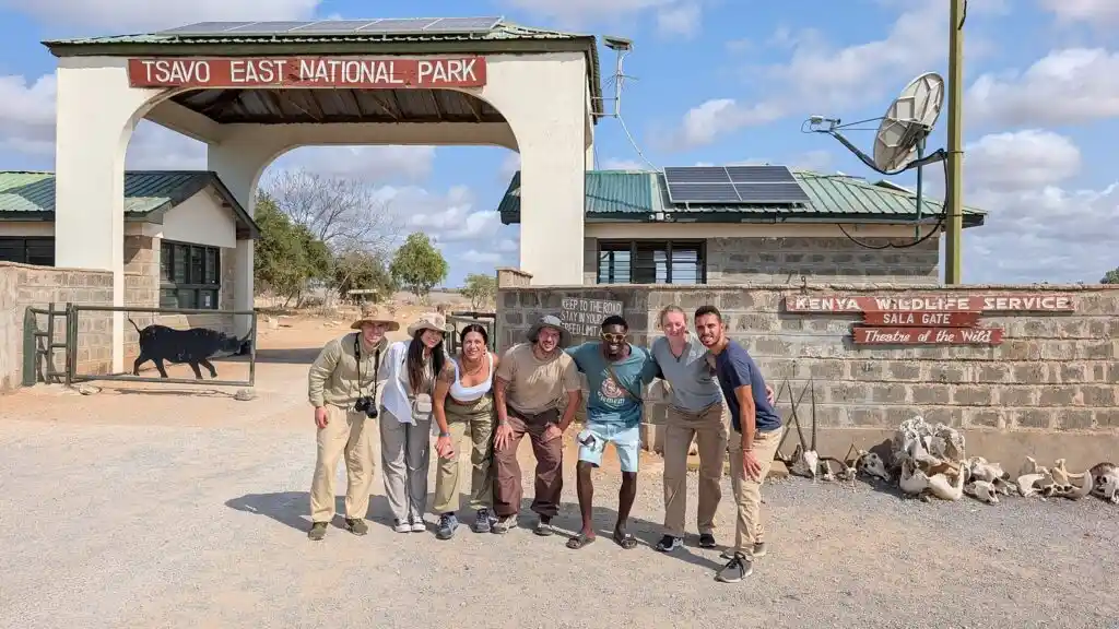 Safari di 6 giorni con Kenya Safari Europa il giorno in cui arriviamo al Parco Nazionale di Tsavo Est, mentre scattiamo una foto di gruppo con Nelson, la nostra guida turistica, mentre ci avviciniamo alla fine del saf